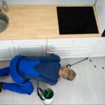Licensed pest control technician inspecting a kitchen for cockroach activity, demonstrating the professional expertise and thorough inspections homeowners should look for when choosing the right pest control company.