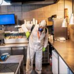 Professional commercial pest control technician inspecting and treating a restaurant kitchen as part of a commercial pest control program to prevent infestations and protect business operations.