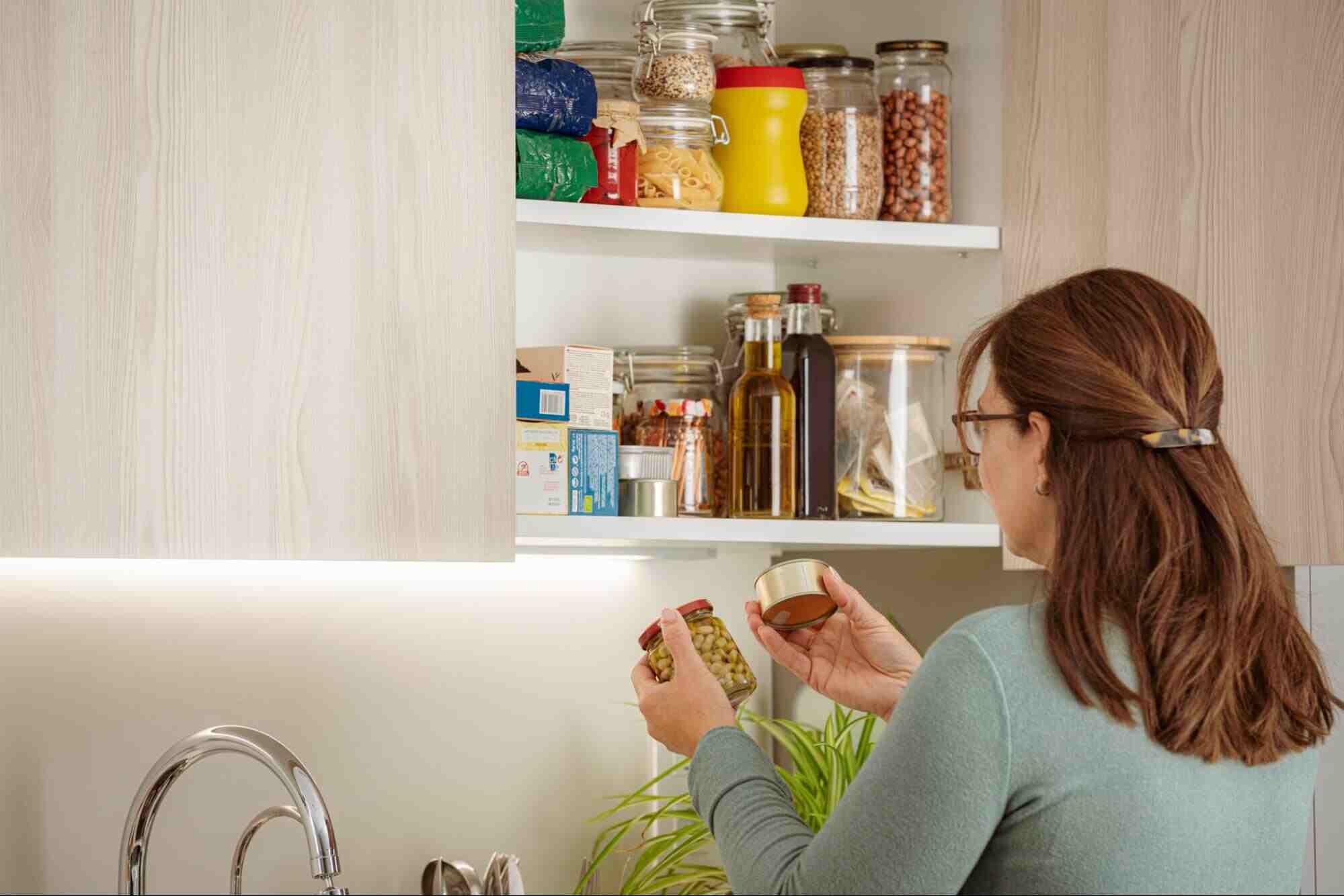 Homeowner organizing pantry containers as part of a pest control checklist for kitchen areas to prevent ants and pantry pests.